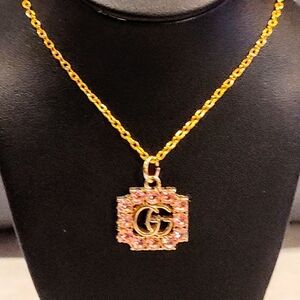 GUCCI GG GOLD TONE PENDANT WITH PINK RHINESTONE ACCENTS ON GOLD PLATED NECKLACE